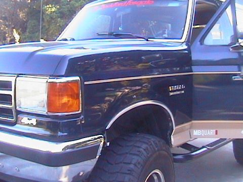1991 Ford Bronco - This 1991 Ford Bronco features a dark blue exterior with chrome accents and prominent off-road tires.
