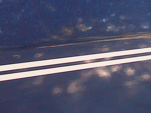 Close-up of white dual pinstripe applied to a dark blue vehicle body panel