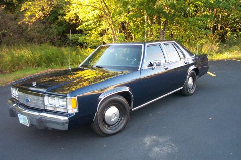 1991 Ford LTD Crown Victoria - This dark blue sedan, likely a 1990 model, is viewed from the front three-quarter angle.