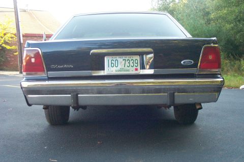 1991 Ford LTD Crown Victoria - The rear of a dark-colored 1991 Ford Crown Victoria LTD is shown, chrome bumpers and a license plate.