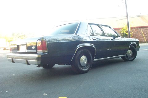 1991 Ford LTD Crown Victoria - The rear of a dark-colored 1991 Ford Crown Victoria is shown from a low angle.