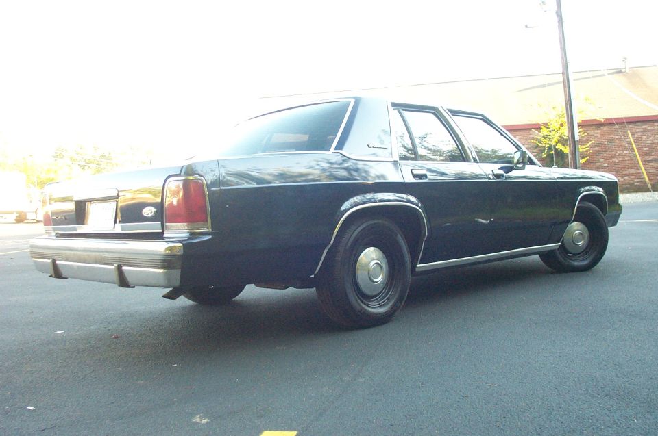 Rear 3/4 view of a dark 1991 Ford Crown Victoria parked on asphalt