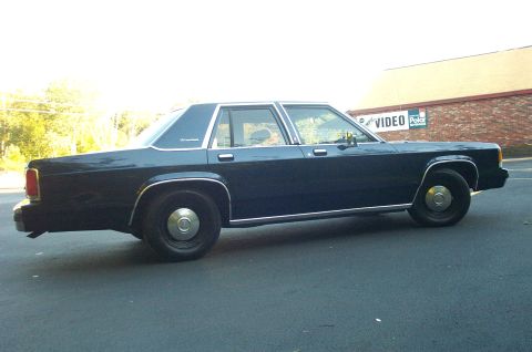 1991 Ford LTD Crown Victoria - A dark blue sedan, likely a 1990 model, is seen from the side with a "Crown Victoria" badge on its rear fender.