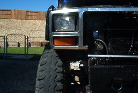 1986 Ford Bronco - Close-up of a truck's front end, revealing the headlight assembly and a large tire.