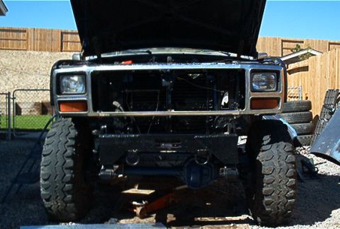 1986 Ford Bronco - This lifted Ford Bronco shows its front end with the hood up and grille removed, revealing the engine bay.