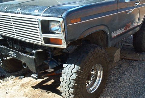 1986 Ford Bronco - Front view of a lifted 1986 Ford Bronco showing the grille, headlight, and off-road tire.