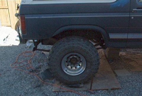 1986 Ford Bronco - The rear section of a Ford Bronco is shown, with a large off-road tire and suspension components visible.