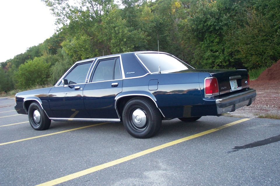 Dark blue Ford LTD Crown Victoria sedan on steel wheels, rear three-quarter view