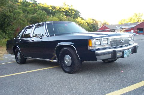 1991 Ford LTD Crown Victoria - A dark blue 1991 Ford Crown Victoria LTD sedan is parked in a lot, showing its front grille and license plate.