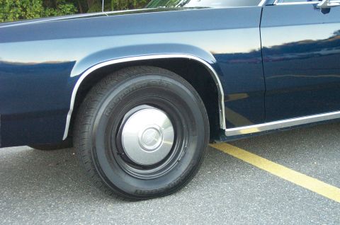 1991 Ford LTD Crown Victoria - Close-up of the front fender and wheel of a dark blue 1991 Ford Crown Victoria LTD, showing chrome trim and a silver hubcap.