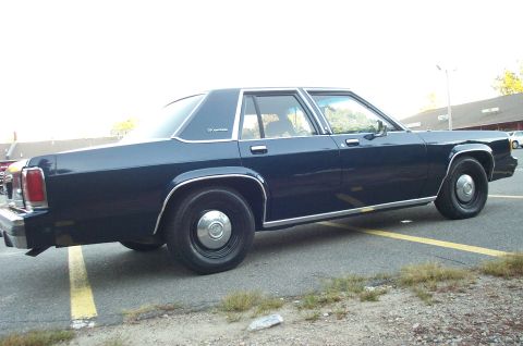 1991 Ford LTD Crown Victoria - Side view of a dark blue 1991 Ford Crown Victoria LTD sedan parked in a lot.