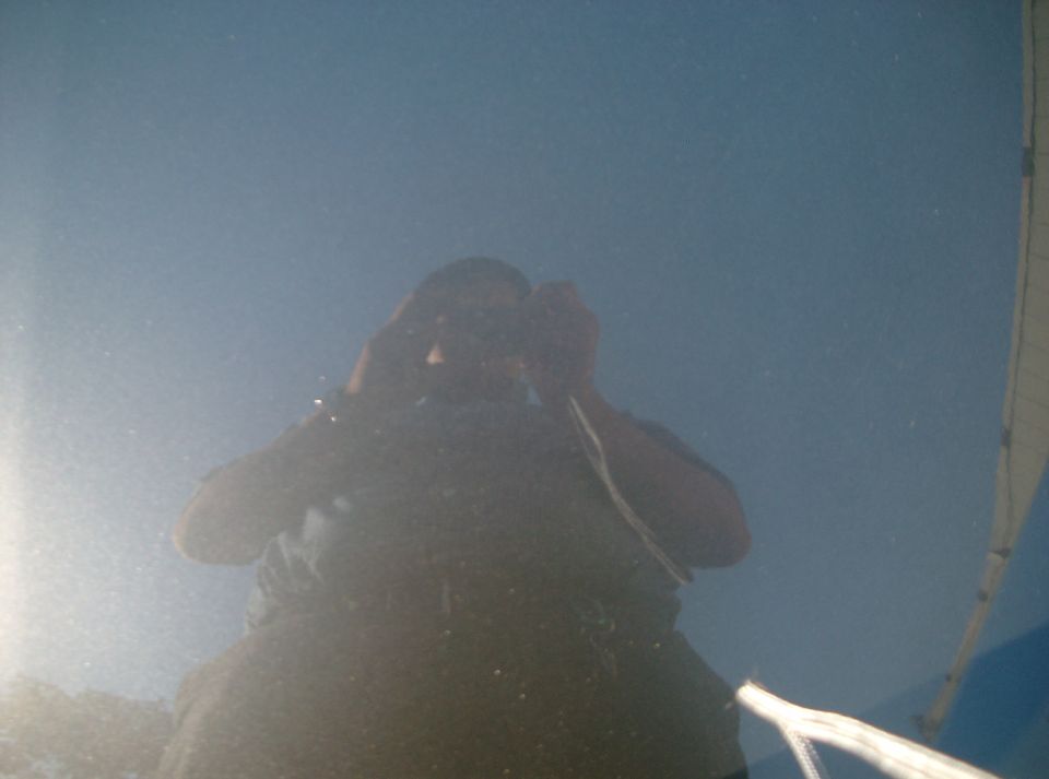Photographer's reflection in a shiny painted vehicle body panel under blue sky