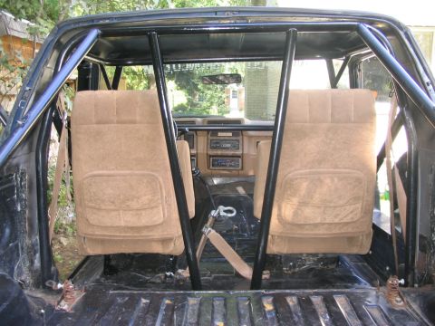 1986 Ford Bronco - The interior of a 1986 Ford Bronco features a prominent roll cage and tan upholstery.