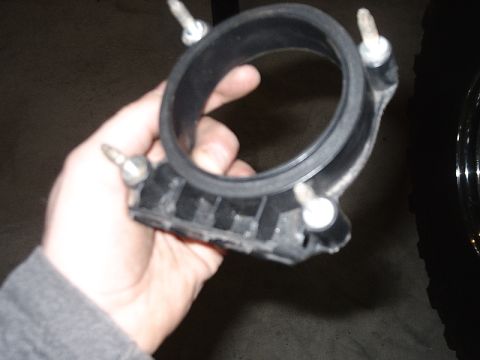 1996 Ford Bronco - A hand holds a black air intake hose clamp, a component of a vehicle's engine system.