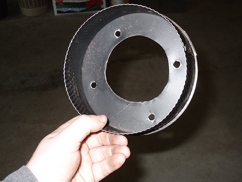 Hand holding a black brake drum showing hub face and lug holes