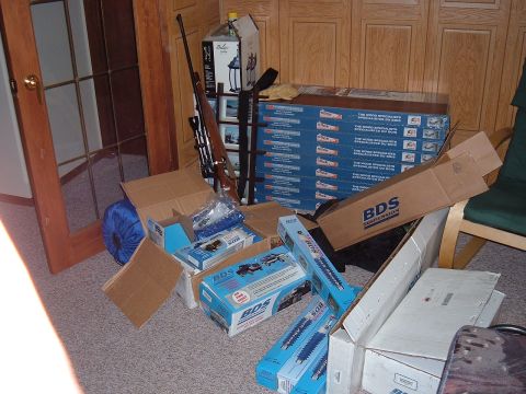 1979 Ford Bronco - Various boxes of BDS suspension parts are piled on the floor next to a rifle and a blue sleeping bag.