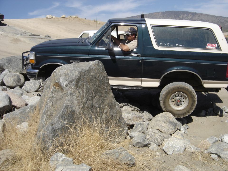 1992 Ford Bronco side view, dark green with white top, off-roading