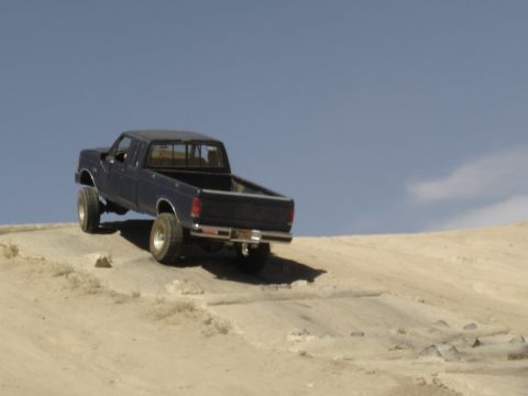 1988 Ford Bronco - Pickup truck navigates an off-road course under a clear blue sky.