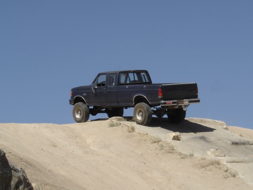 Dark blue Ford F-Series pickup truck with lifted suspension on a dirt hill