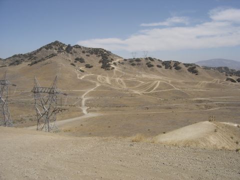 1988 Ford Bronco - Off-road trails wind through a dry, hilly landscape with power line towers dominating the view.