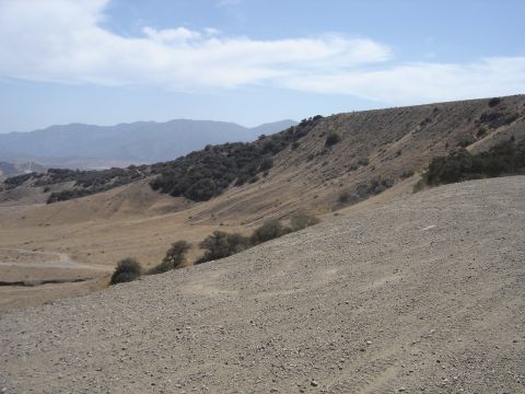 1988 Ford Bronco - A wide view of a dry, hilly terrain with sparse vegetation and mountains in the distance. The Supermotors logo is visible in the bottom rig…