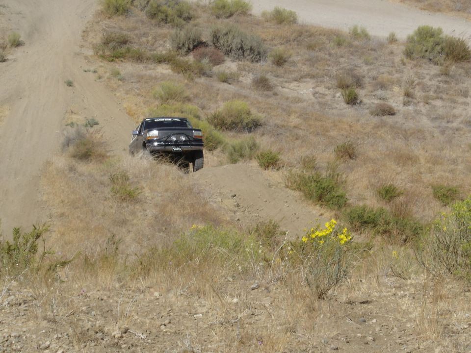 Black pickup truck with a brush guard driving on a dirt hill