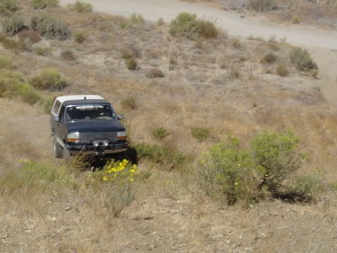 1988 Ford Bronco - Ford Bronco navigates a dry, grassy hillside on a dirt path.