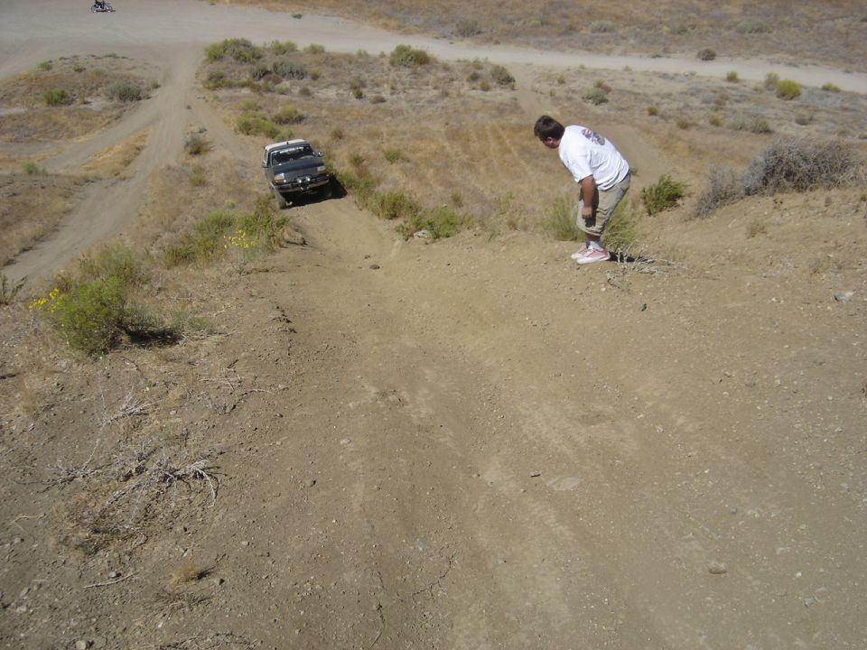 Black Ford Bronco driving down a dirt hill, driver looking down