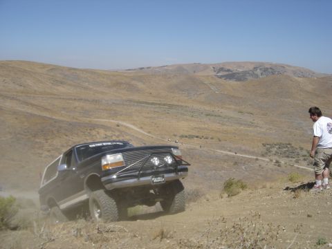 1988 Ford Bronco - Ford Bronco navigates a steep, dusty trail in a dry, hilly landscape.