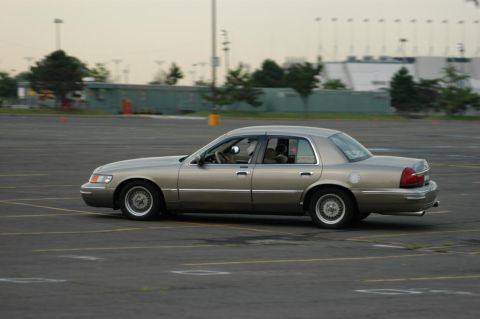 2001 Mercury Grand Marquis - Tan 2001 Mercury Grand Marquis sedan seen from the side on an asphalt lot.