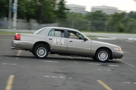 2001 Mercury Grand Marquis - A tan 2001 Mercury Grand Marquis is captured in motion, displaying a distinctive '888' graphic on its side.