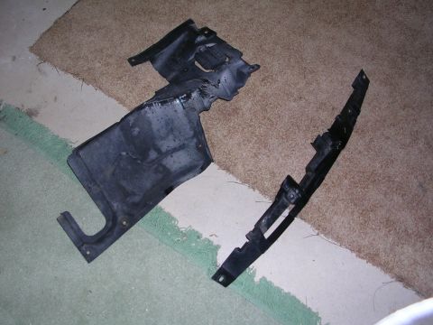 2003 Chevrolet Monte Carlo - Two black plastic automotive underbody panels are shown laid out on a carpeted floor.