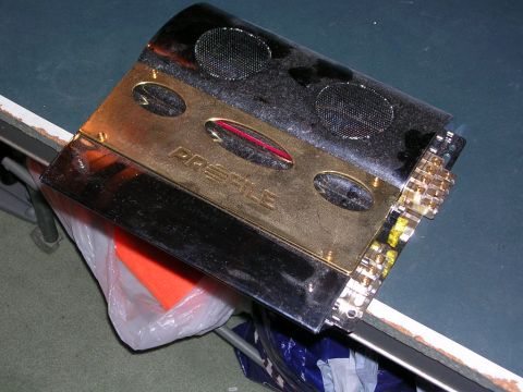 2003 Chevrolet Monte Carlo - A car amplifier with a gold faceplate and black casing is shown from an angled perspective.