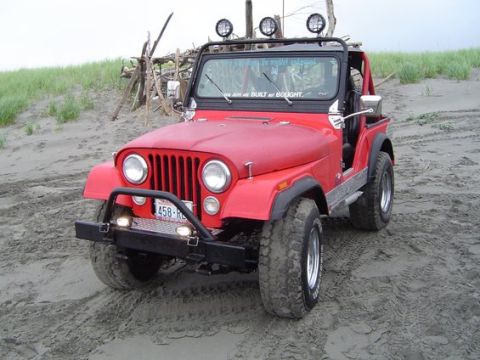 1993 Ford Bronco - This red Jeep CJ-7 is equipped with off-road lights and sits on a sandy terrain.