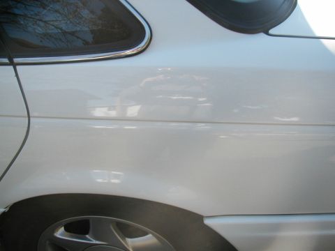 1993 Ford Taurus - The side of a white car is shown, focusing on the rear wheel well and a portion of the body panel.