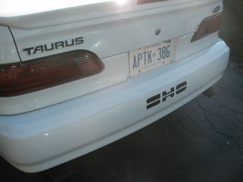 1993 Ford Taurus - Rear view of a white 1993 Ford Taurus, showing the license plate and a SHS decal on the bumper.