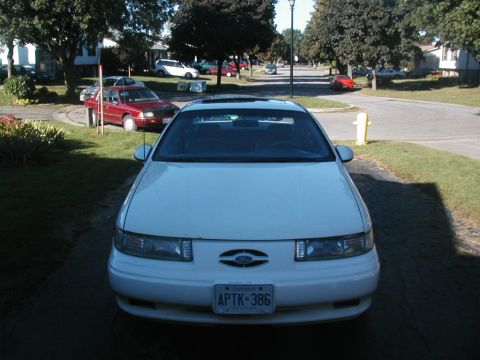 1993 Ford Taurus - A white 1993 Ford Taurus is parked in a suburban driveway on a sunny day.