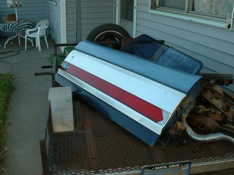 1990 Ford Bronco - Car door and spare tire on a trailer, possibly for sale.