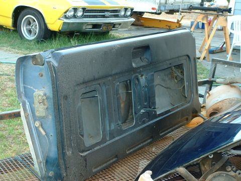 1990 Ford Bronco - A detached vehicle tailgate is shown, with a yellow car visible in the background.