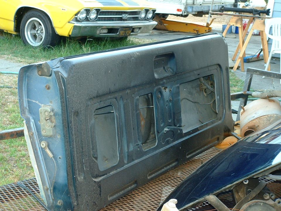Tailgate removed from a vehicle, sitting on a trailer. Yellow car in background