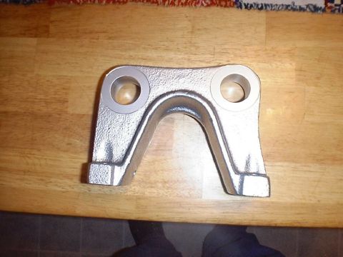 1988 Ford Bronco - Top view of a rough-cast U-shaped suspension/axle bracket with two large machined bores flanking an arched center saddle, its bare metal sh…