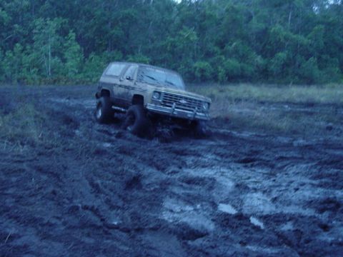 1989 Ford Bronco - A Chevrolet K5 Blazer is stuck in deep mud with trees in the background.