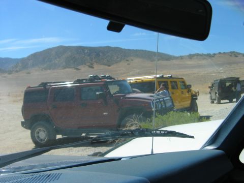 1985 Ford Bronco - Three Hummer H2 SUVs are parked in a dry, hilly landscape under a clear blue sky.