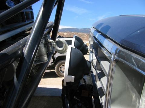 1985 Ford Bronco - Two vehicles, one with a roll cage and hook, the other showing its grille and auxiliary lights.