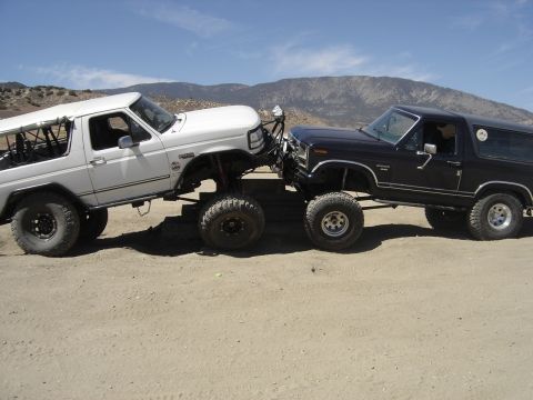 1987 Ford F-250 - Two modified Ford Broncos appear to be in a standoff on a dusty trail.