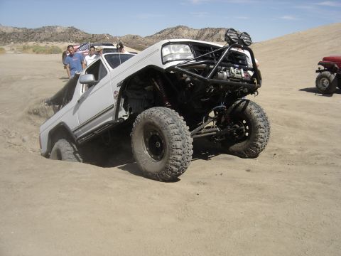 1987 Ford F-250 - This heavily modified off-road truck is stuck in the sand, its custom suspension and large tires.