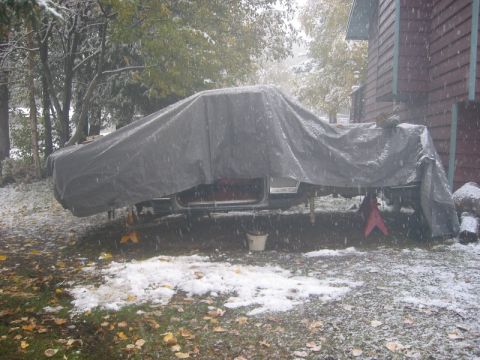 1985 Ford Bronco - A vehicle sits covered by a tarp in snowy weather, suggesting it is being stored or worked on outdoors.