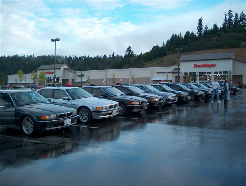 Row of BMW 7 Series sedans in a wet lot outside a Fred Meyer store