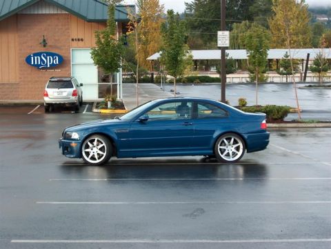 1999 BMW 7 Series - A blue coupe is parked in a wet parking lot next to a building with a sign that says 'inSpa'.