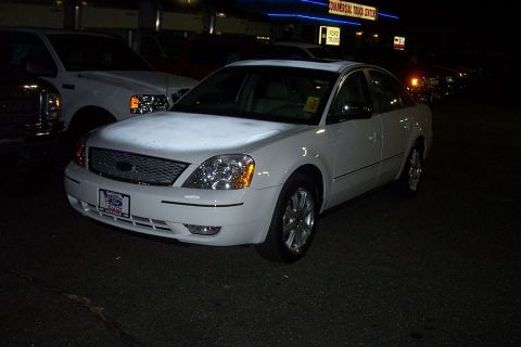 1993 Ford Taurus - White sedan parked outside a commercial truck center at night, with other vehicles nearby.